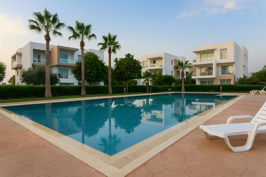 a swimming pool in front of a building with palm trees at Résidence Tafoult Imiouadar près de Taghazout Agadir in Imi Ouaddar
