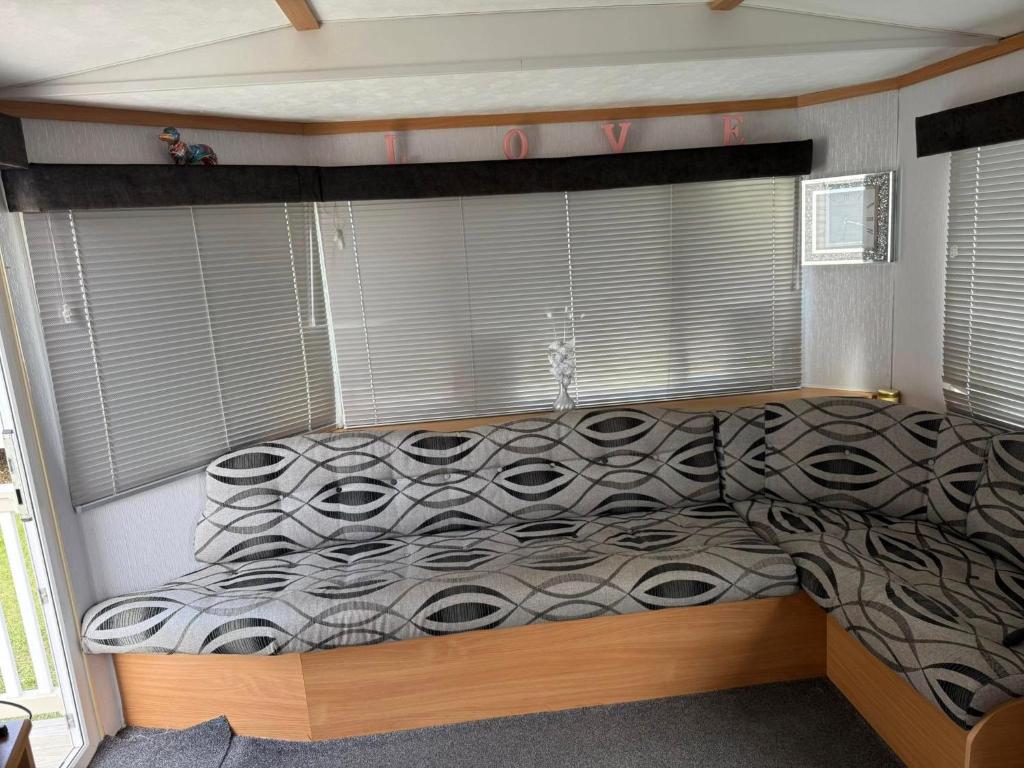 a bedroom with a bed with a comforter and windows at Seaside Getaways Caravan Hire in Chapel Saint Leonards