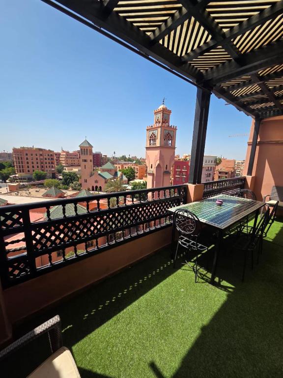 a balcony with a table and a clock tower at andalous 4 in Marrakesh