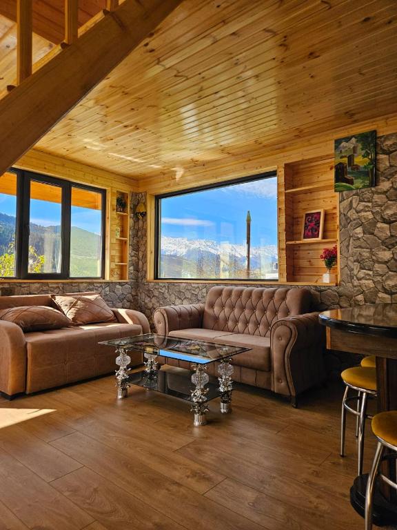 a living room with couches and a stone wall at Hilltop cottage Mestia in Mestia