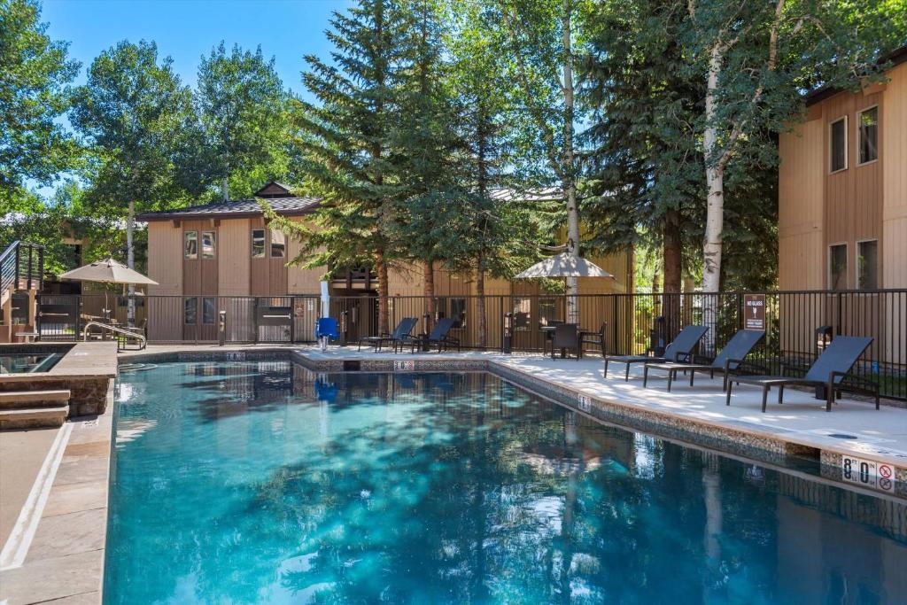 a swimming pool at a apartments with chairs and trees at Woodbridge 27E in Snowmass Village