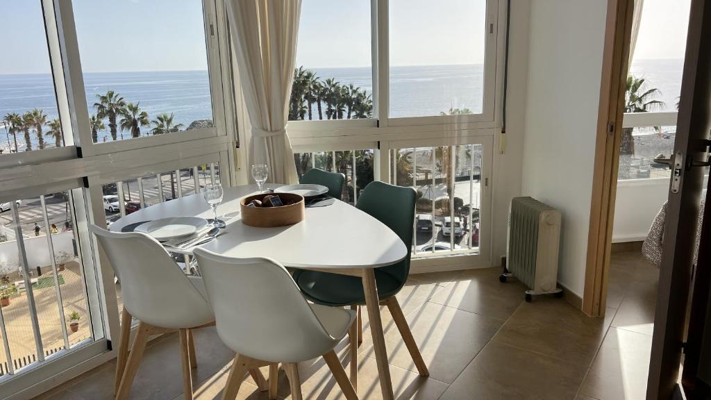 a dining room with a white table and chairs and windows at Ruselo in Torrox Costa