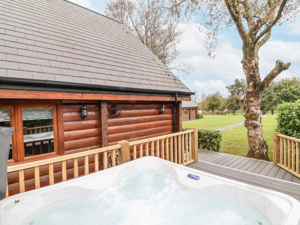 a hot tub on a deck next to a cabin at Willow in Winkleigh