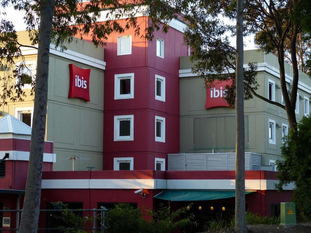 um edifício vermelho com o sinal do autocarro em ibis Thornleigh em Thornleigh