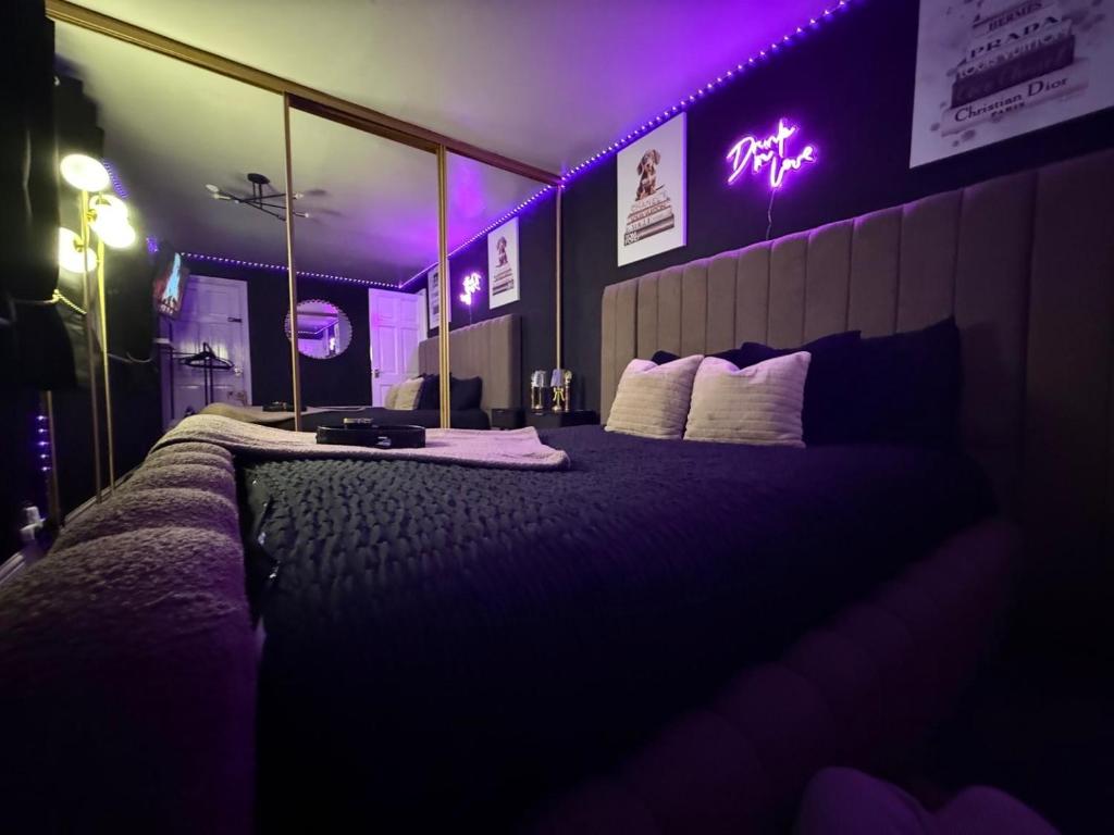 a bedroom with a large bed with purple lighting at A Star Living in Liversedge