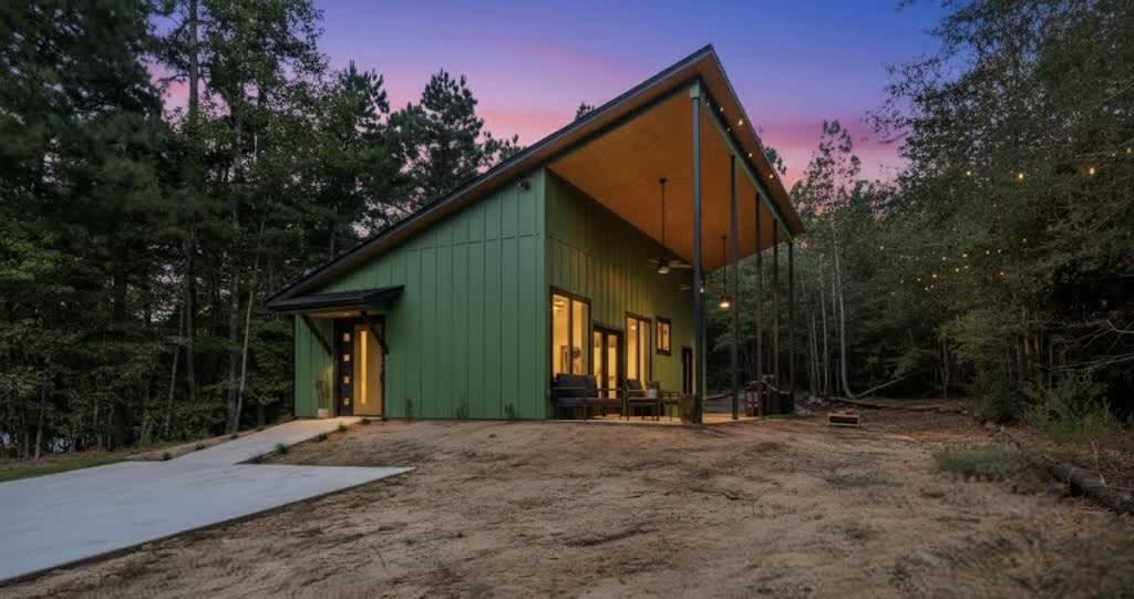 a green building in the middle of a forest at Modern Cabin Retreat Easy Drive to Canton and Tyler in Chandler