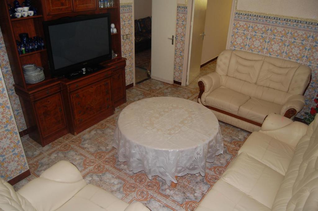 ein Wohnzimmer mit einem Sofa, einem Tisch und einem TV in der Unterkunft Appartement alhoceima in Al Hoceïma
