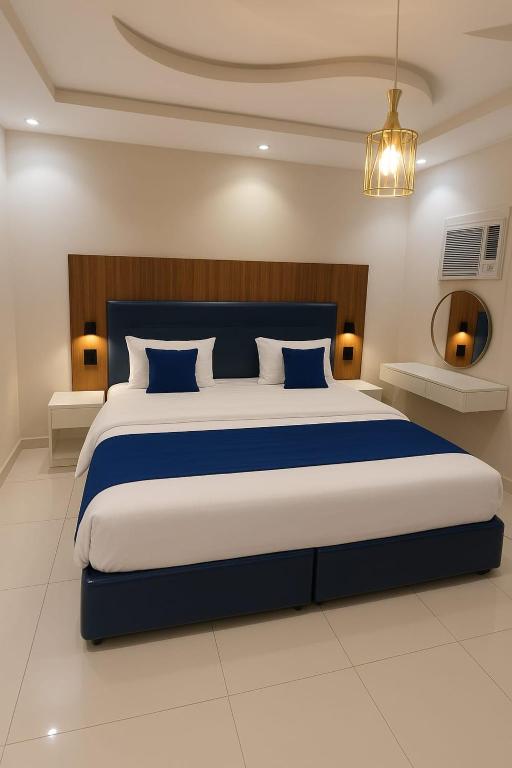 a bedroom with a large bed with blue and white pillows at شوران الأولى in Medina