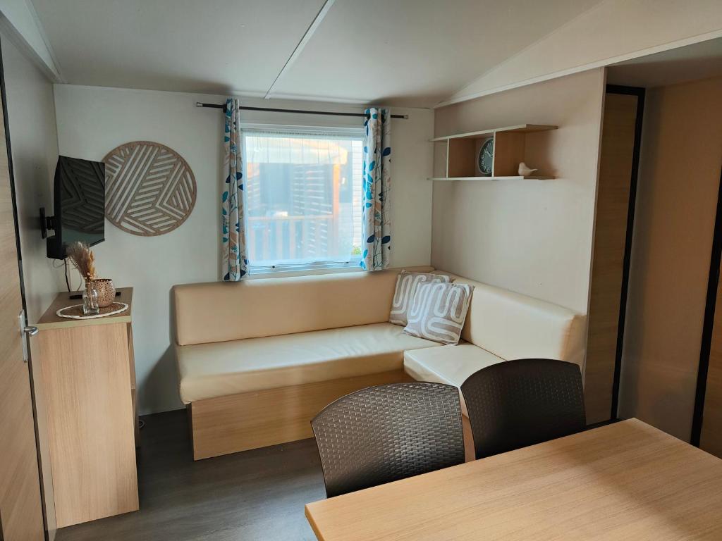 ein kleines Wohnzimmer mit einem Sofa und einem Fenster in der Unterkunft La Petite Maison du Park in Boofzheim