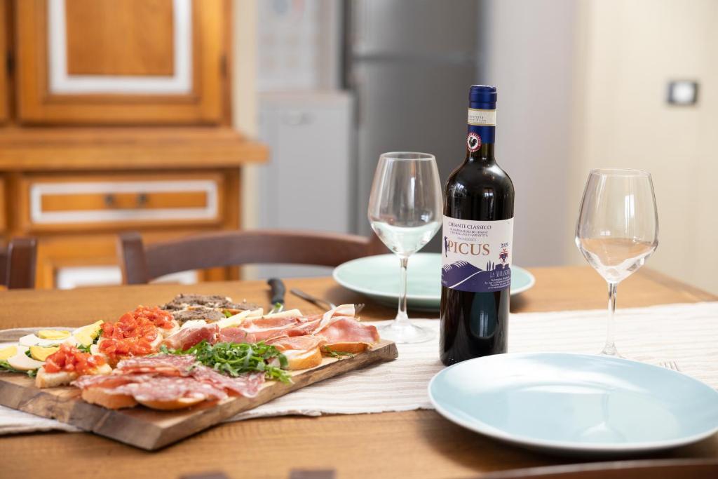Una botella de vino y una pizza en una mesa con vasos. en Casa Bruna - Cipresseta del Chianti, en Castellina in Chianti