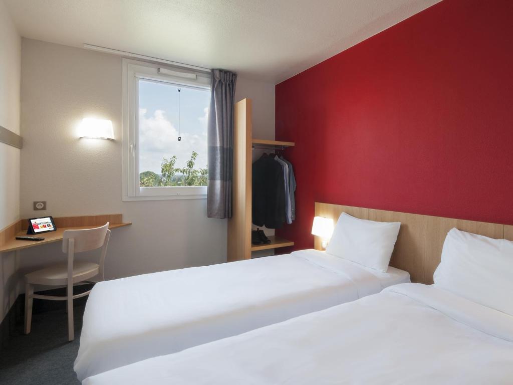 a hotel room with two beds and a window at B&B HOTEL Paray-le-Monial in Paray-le-Monial