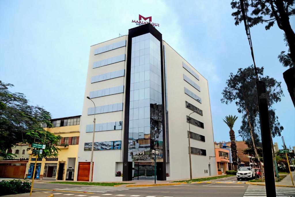 a tall white building with a sign on it at Mariategui Hotel & Suites in Lima