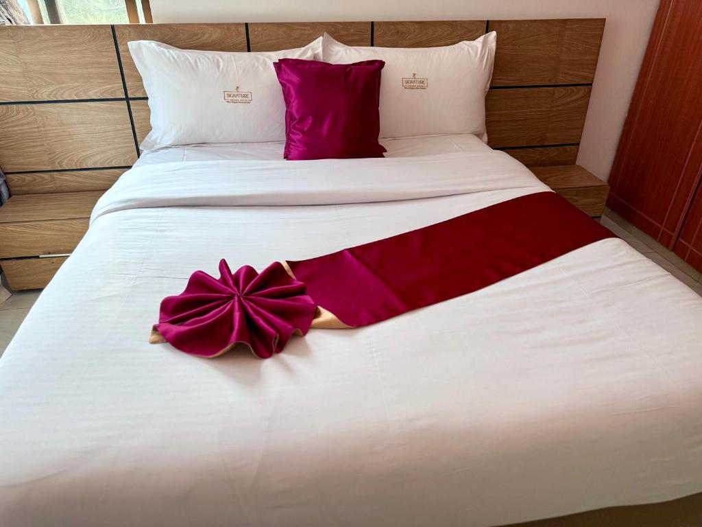 a large white bed with a purple bow on it at Signature Resort Hotel Jinja in Jinja