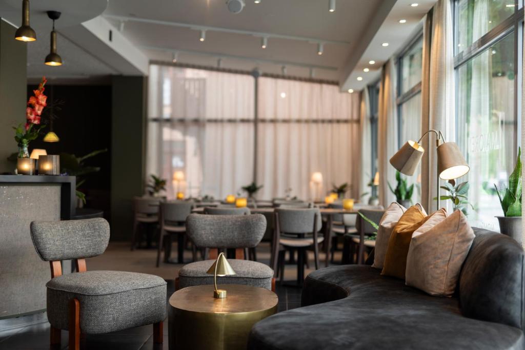 a restaurant with a couch and chairs and tables at Home Hotel Majoren in Skövde