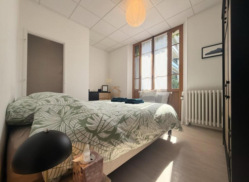 a bedroom with a bed with a green comforter at Le Cathedral Hyper Centre Parking Balcon in Saint-Jean-de-Maurienne