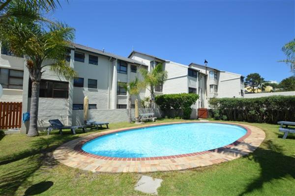 a swimming pool in a yard next to a building at Laridae Getaway in Plettenberg Bay