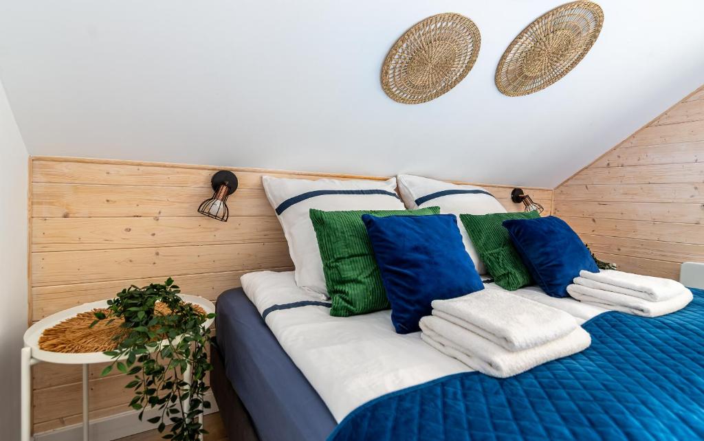 a bed with blue and green pillows on it at Domek W Sosnach Poleski Park Narodowy in Grabniak
