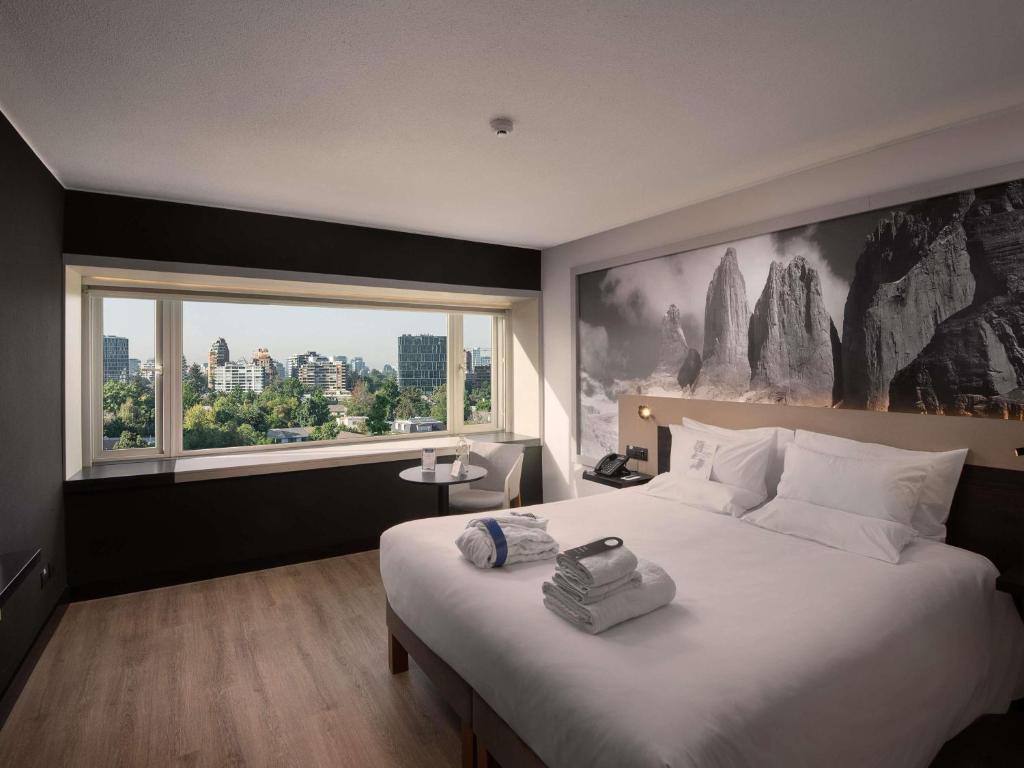 um quarto com uma cama grande e uma janela grande em Novotel Santiago Vitacura em Santiago