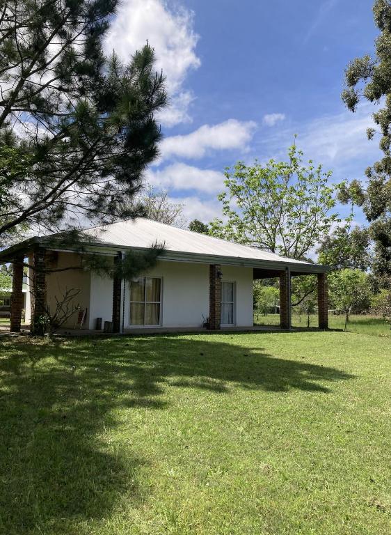 a small white house with a tree in the yard at Casa de playa Camping Chajarí in Santa Ana