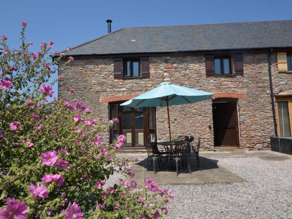 einem Tisch mit einem Regenschirm vor einem Gebäude in der Unterkunft 2 Bed in Totnes 61775 in Ipplepen