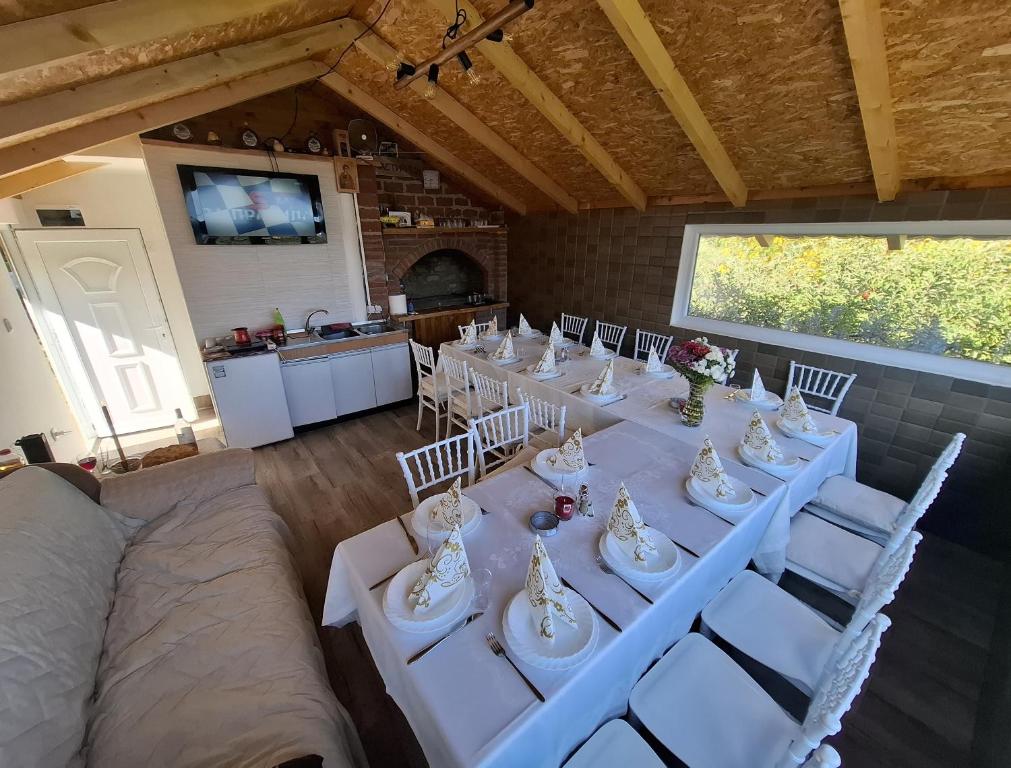 a room with a long table and white chairs at Kućica na žaru in Čačak