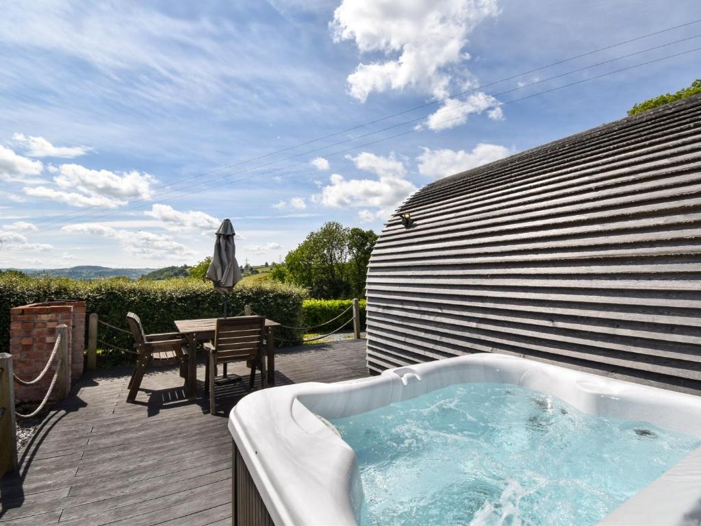 Una bañera de hidromasaje en una terraza con una mesa. en 1 Bed in Gwyddelwern 80319, en Gwyddelwern