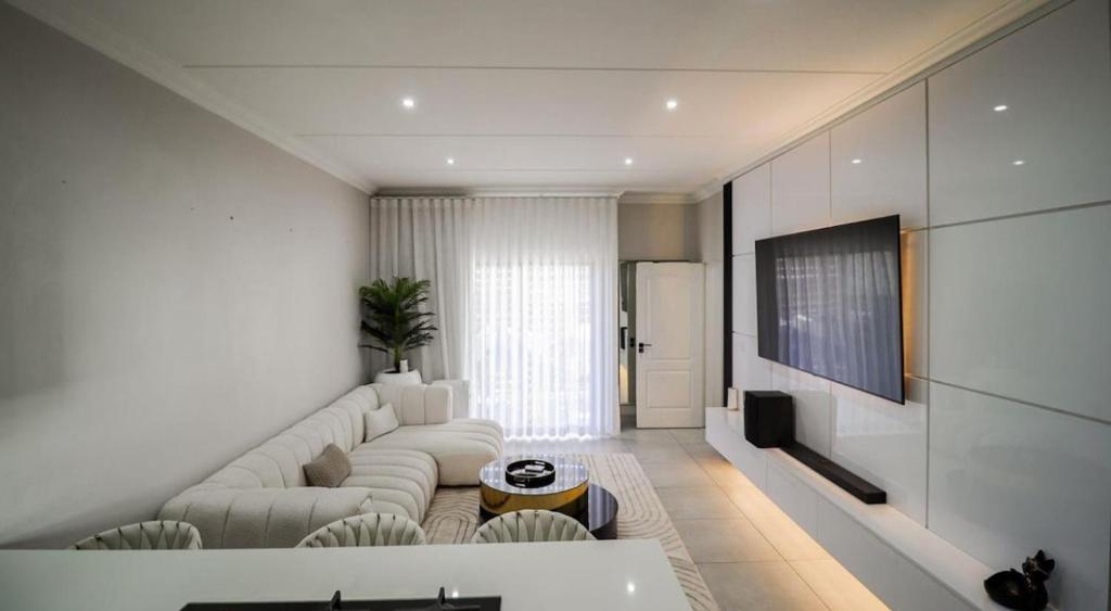 a living room with a white couch and a tv at LiFa Luxury Sandton Retreat in Johannesburg