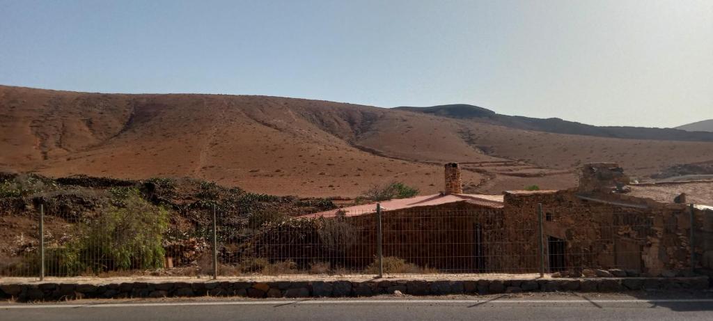 a building with a fence in front of a mountain at Villa Mirador de la Loma in Pájara