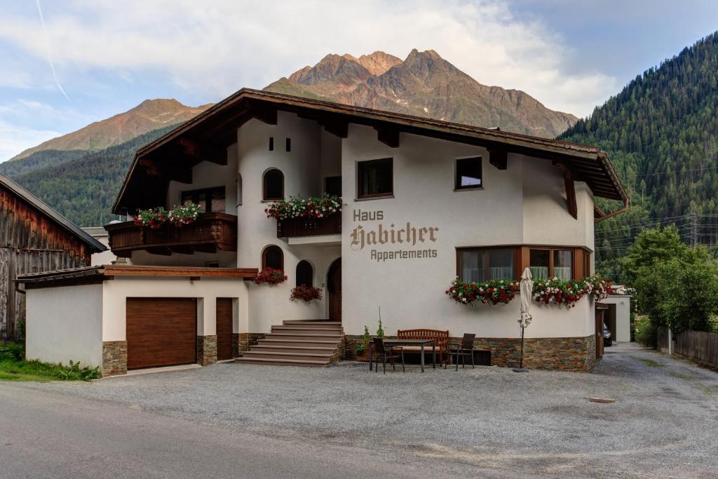 ein großes weißes Gebäude mit Bergen im Hintergrund in der Unterkunft Appartement Habicher in Pettneu am Arlberg