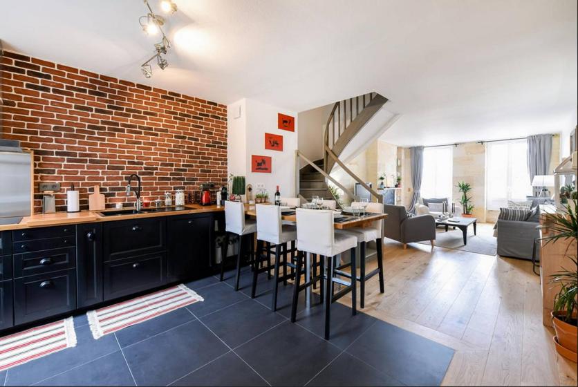 Il dispose d'une cuisine et d'un salon avec un mur en briques. dans l'établissement Duplex Centre Historique, à Bordeaux