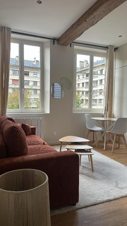 a living room with a couch and a table and windows at T2 chaleureux au centre de la ville in Rouen