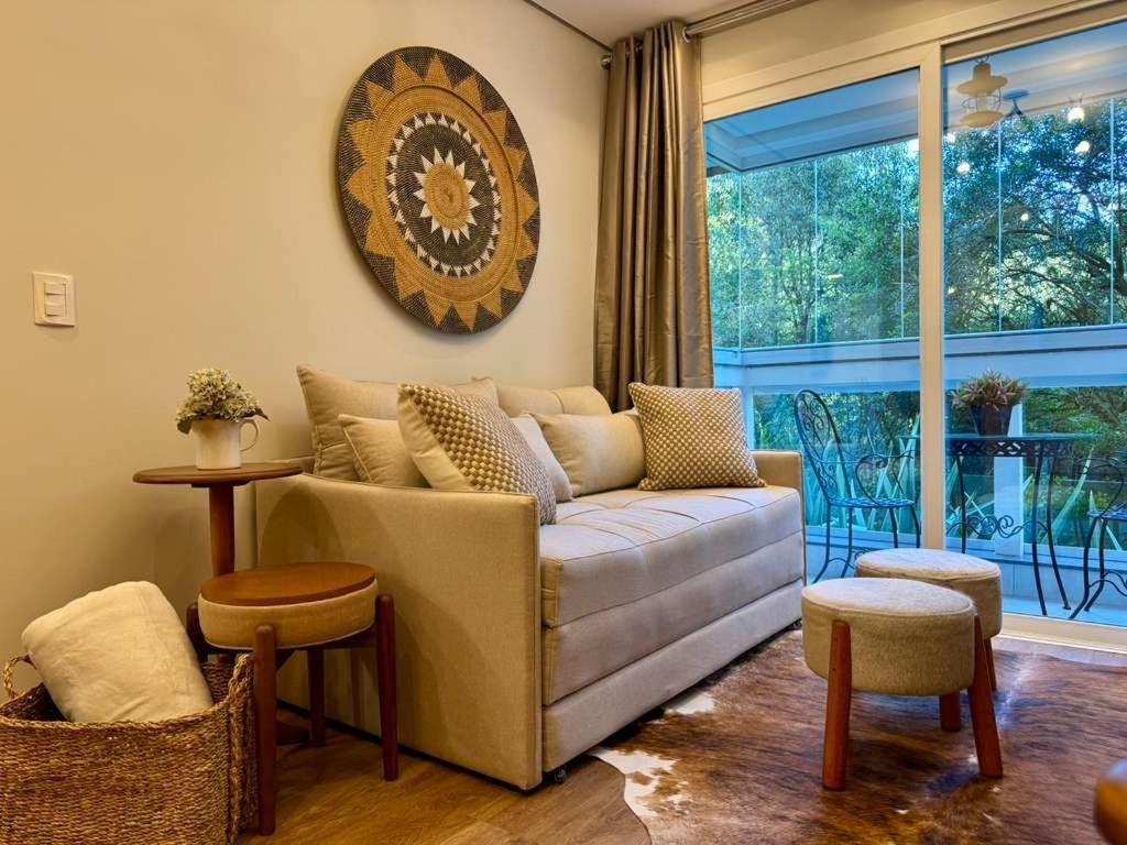 a living room with a couch and a large window at Delle Alpi 117 - Apartamento novo junto a Nasa e roda-gigante in Canela