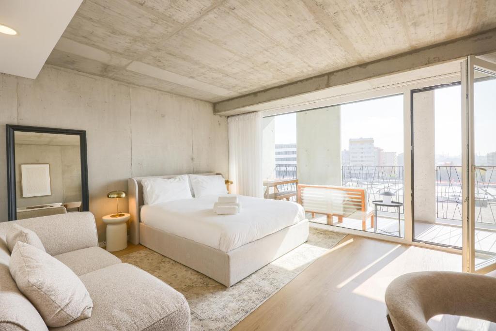 a bedroom with a white bed and a large window at * Blanc Studio Aveiro * in Aveiro