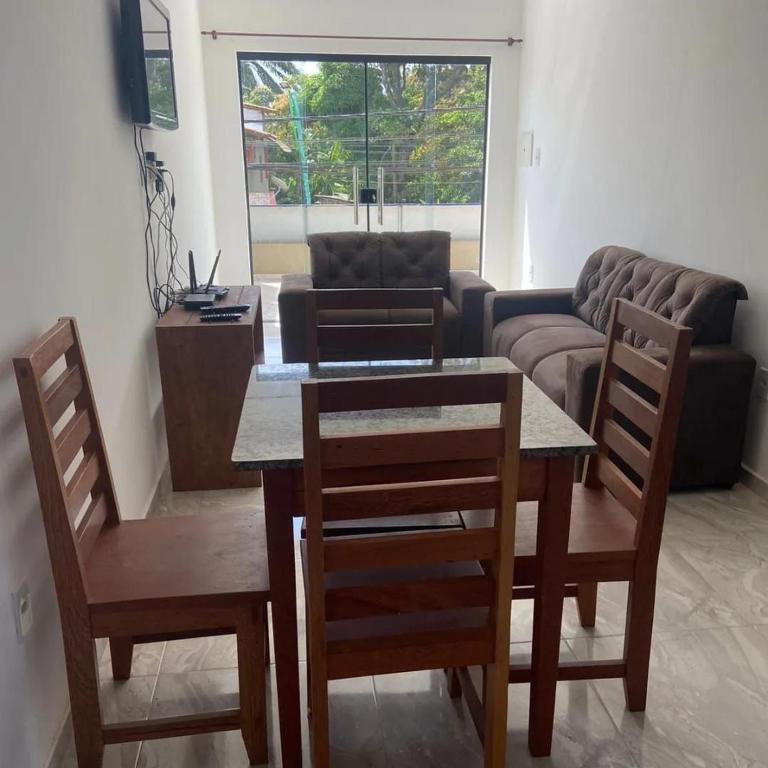 un salon avec une table, des chaises et un canapé dans l'établissement Apart Lua Cheia 2 quartos caminho das praias, à Itacaré