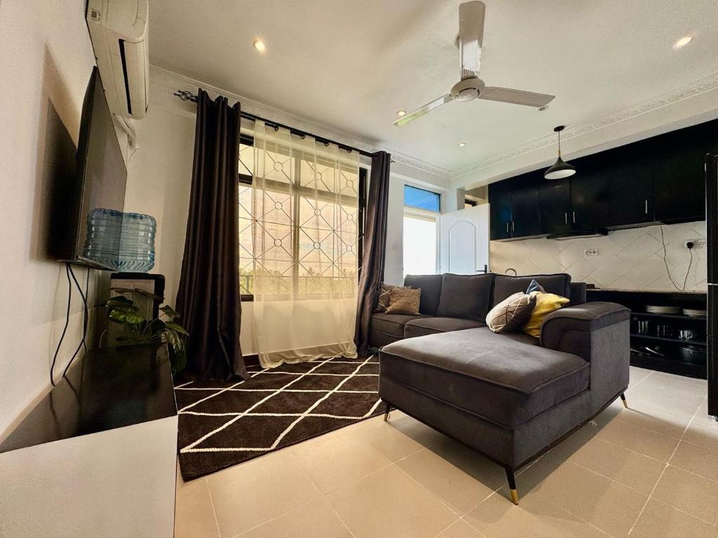 a living room with a couch and a ceiling fan at IVORY Home 2 in Dar es Salaam