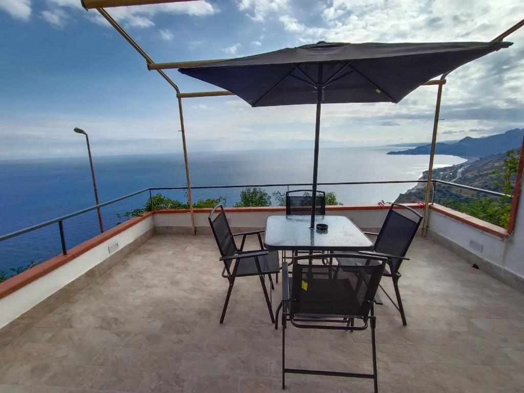 a table and chairs on a balcony with an umbrella at MAISON PALMENTELLo 3 in Forza dʼAgro
