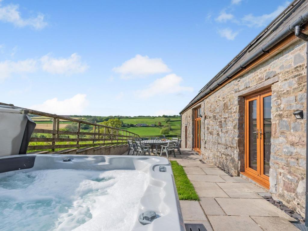 a hot tub on the patio of a stone house at 4 Bed in Kidwelly CWRTY in Kidwelly