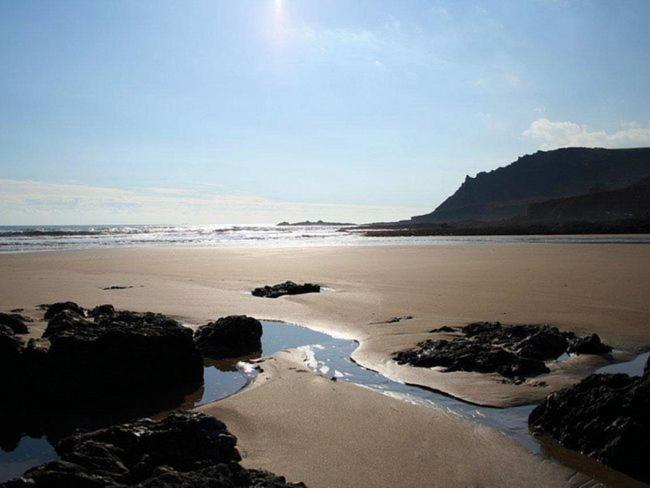 a beach with rocks and the ocean on a sunny day at 2 bed property in South Allington FERN3 in South Pool