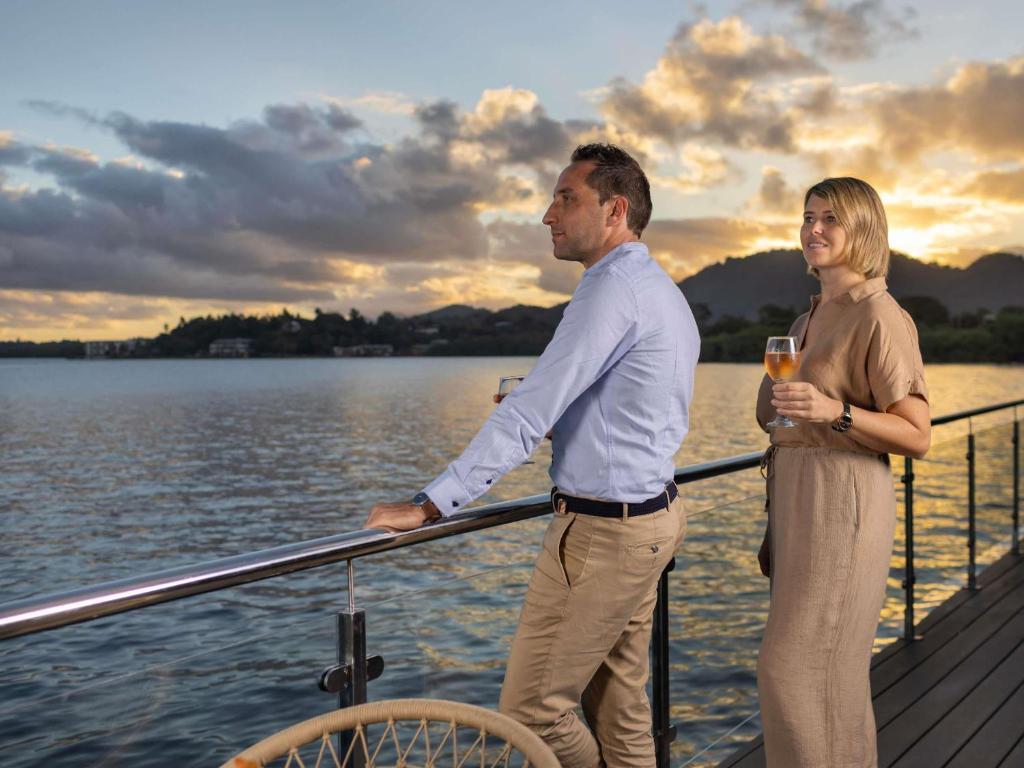 a man and woman standing on a dock with a glass of wine at Novotel Suva Lami Bay in Suva