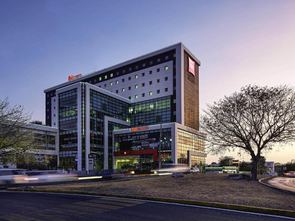 een hoog gebouw met auto's ervoor bij Ibis Cancun Centro in Cancun