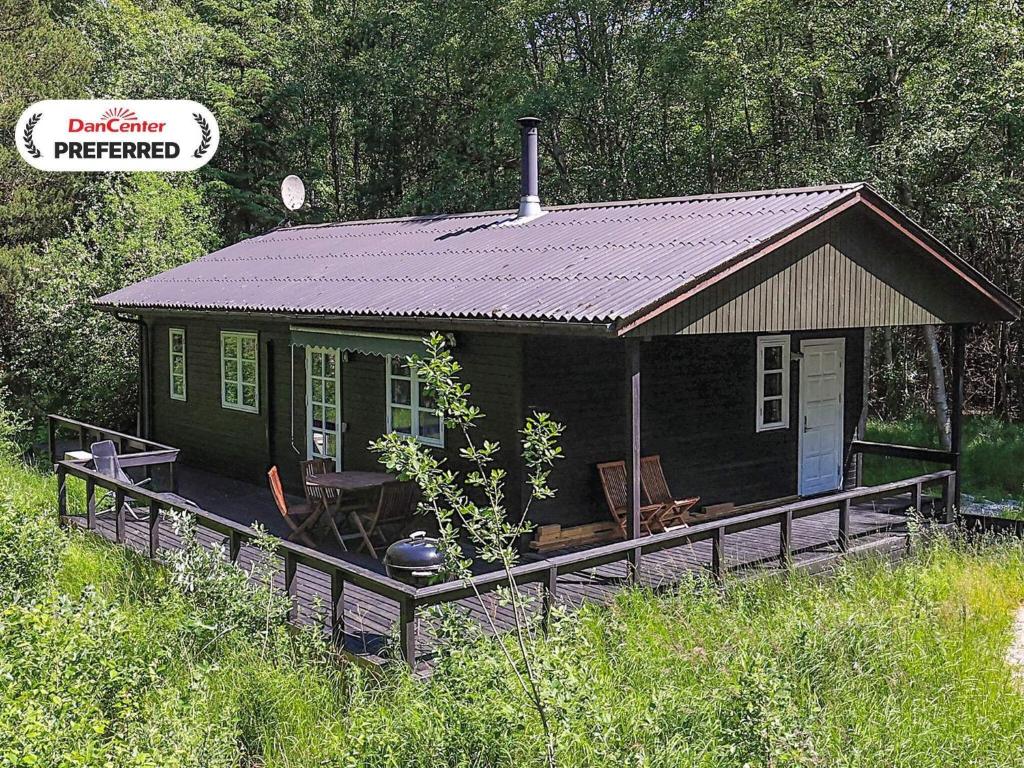 a small green house with a porch in a field at 4 person holiday home in Læsø in Læsø