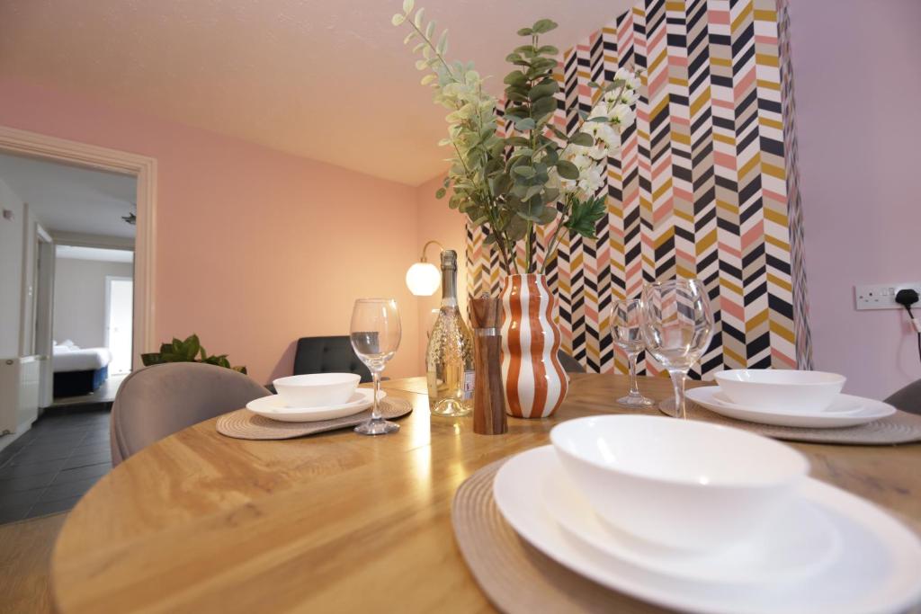 a dining room table with white plates and wine glasses at Stylish central location 3 bedroom house in Ely