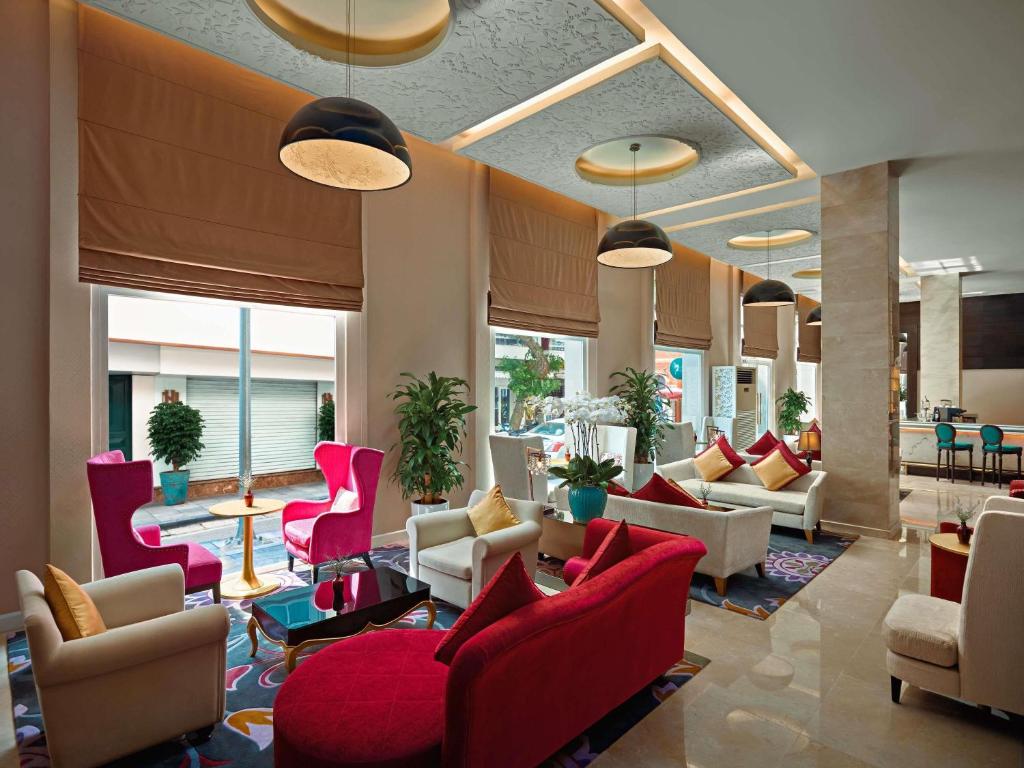 a lobby with red chairs and couches in a building at Hotel de l’Opera Hanoi - MGallery in Hanoi