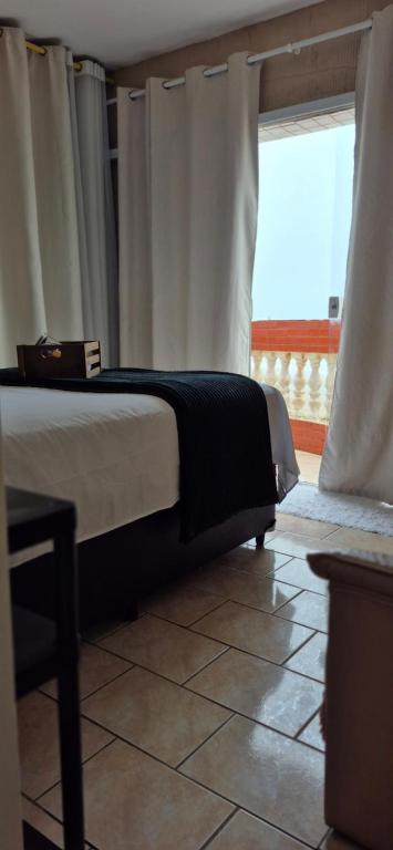 een slaapkamer met een bed met gordijnen en een raam bij Apartamento com vista para o mar in Mongaguá