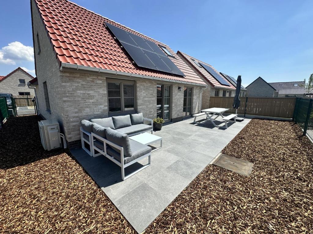 a patio with a couch and a table and a roof at Westhinder II H28 in Witte Burg