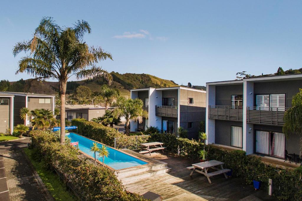 an apartment complex with a swimming pool and palm trees at Sea Views at 7 - Beachside Apartment in Whitianga