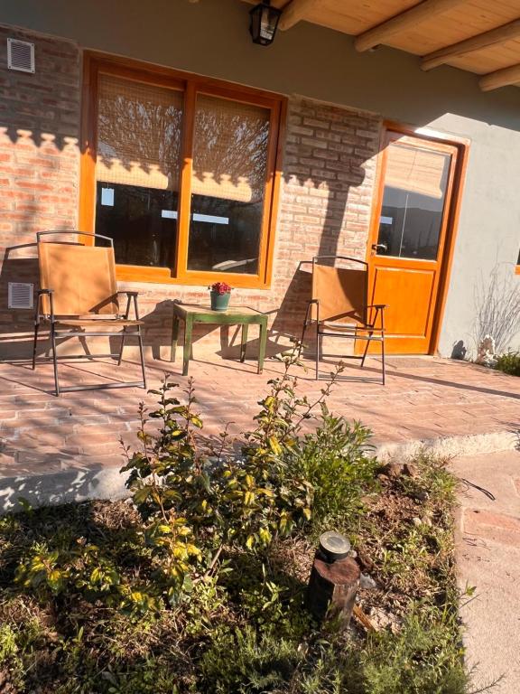 two chairs and a table in front of a house at Ranchos de la Tata in Las Calles