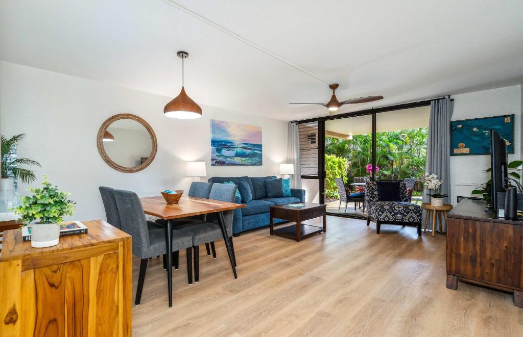 a living room with a blue couch and a table at Charming Beachside Garden Vistas in Wailea