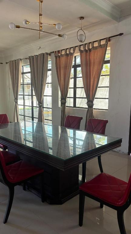 a glass table with red chairs in a room with windows at Cwa Homestay in Kampong Molek