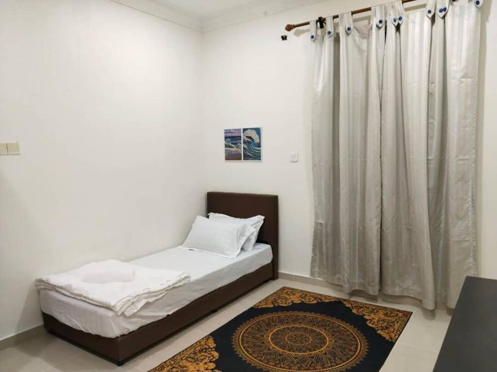 a bed in a room with a curtain and a rug at Cwa Homestay in Kampong Molek